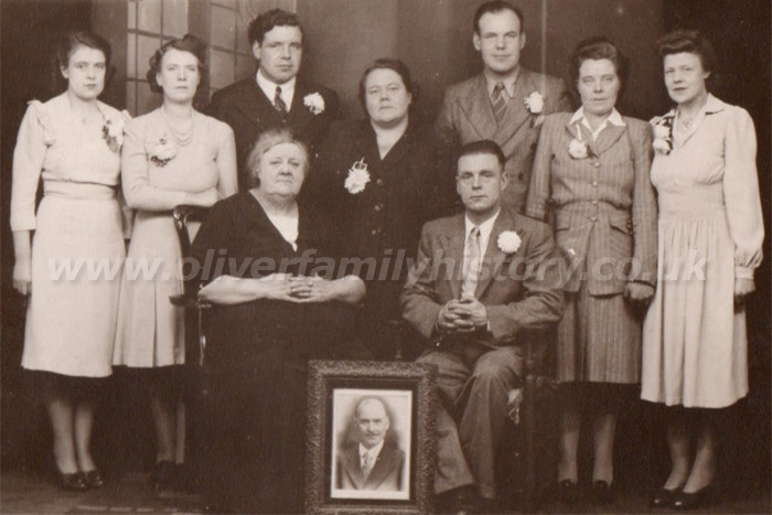 This is a photograph of Mary Ann Oliver (nee King) and her family.Mary Ann is the wife of George William Oliver, who was the Grandson of Stephen Oliver who was born in Stonesfield but moved to the North West in the early 1870's.The photograph includes Olga, Gladys, Frederick, Mary Ann (seated), Mary Ann (known as Molly), George William Oliver (framed picture), George (seated), Charles, Mabel and Evelyn.